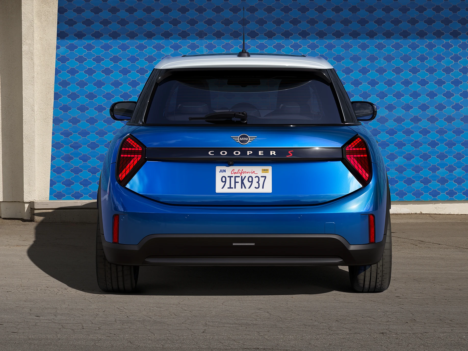Heckansicht eines MINI Cooper 5-Türer in Icy Sunshine Blue mit Dach in Multitone Blue.