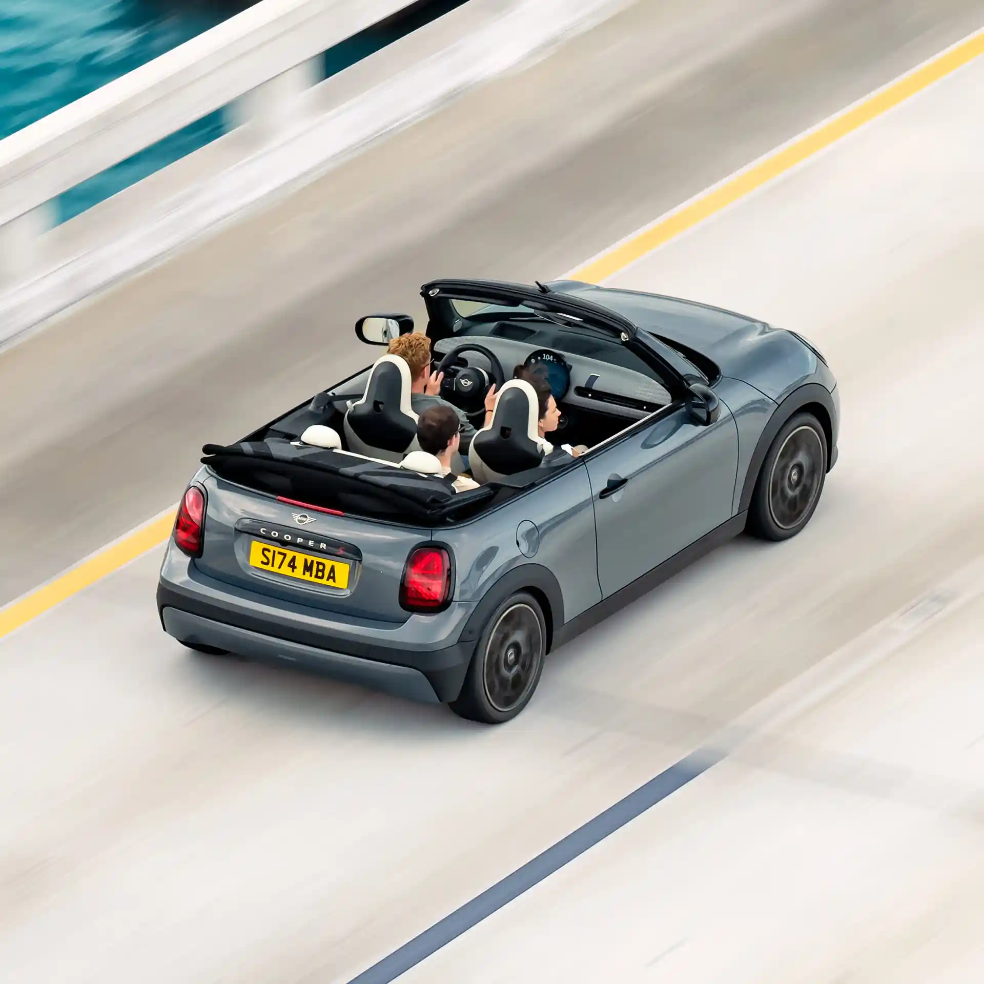 Ansicht von hinten oben auf ein MINI Cooper Cabrio, das auf einer Straße fährt