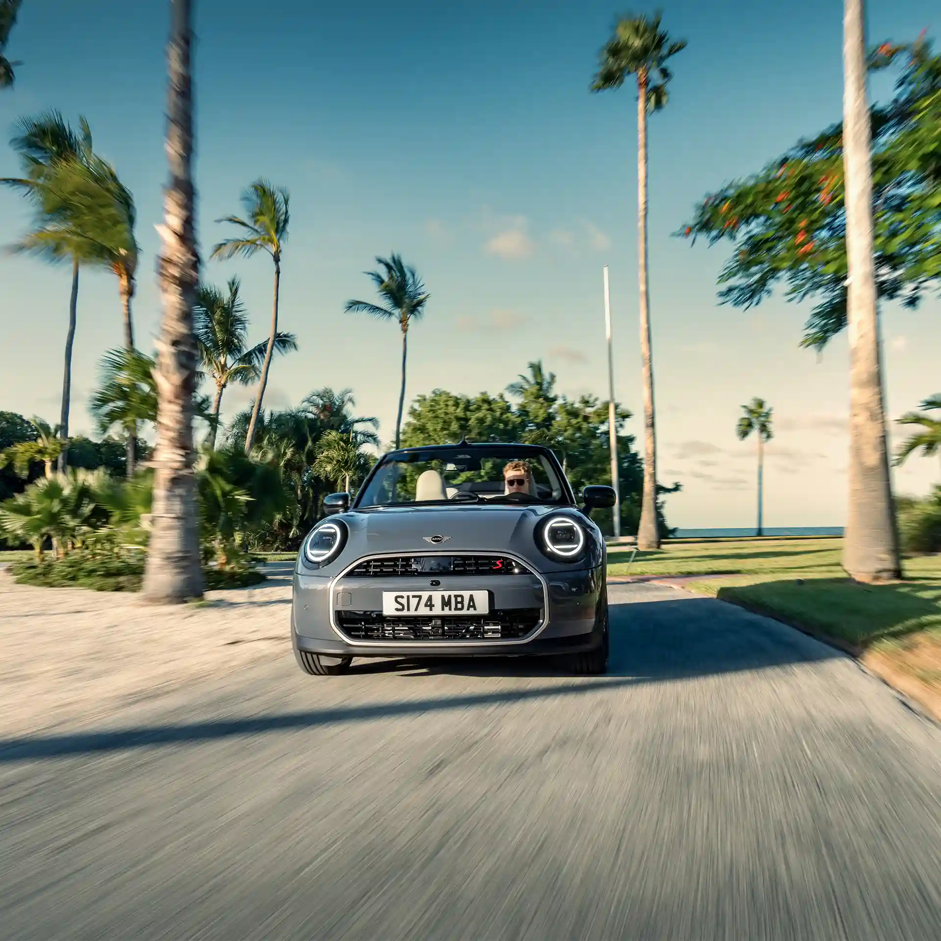 Frontansicht eines MINI Cooper Cabrio in Copper Grey, das auf einer Straße fährt