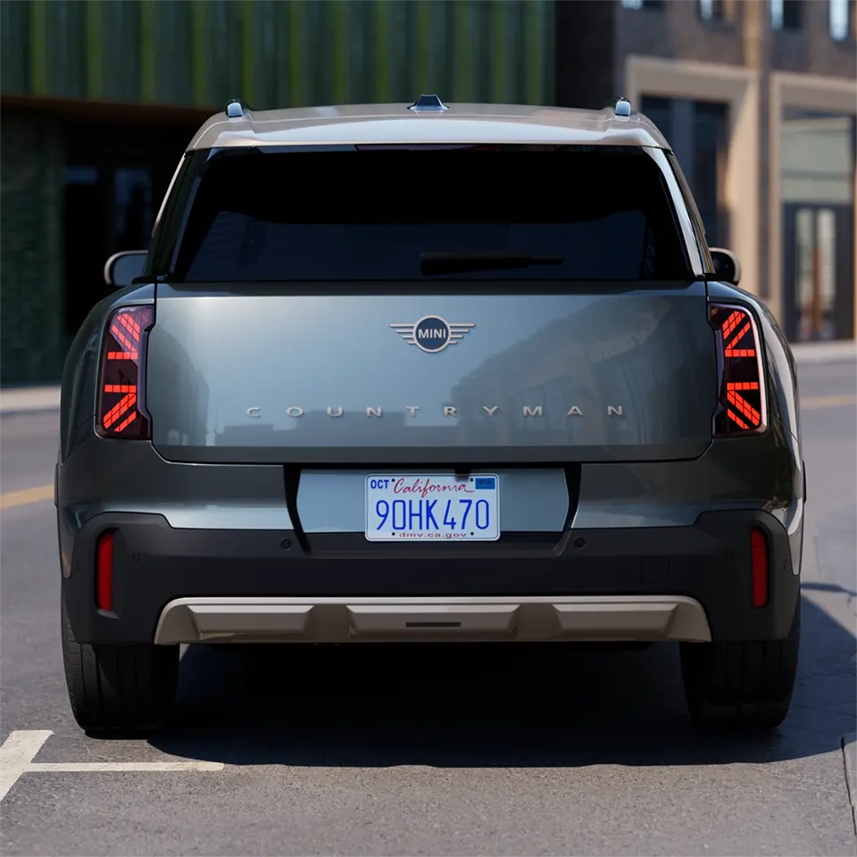 Heckansicht eines parkenden MINI Countryman in Smokey Green mit Dach in Vibrant Silver