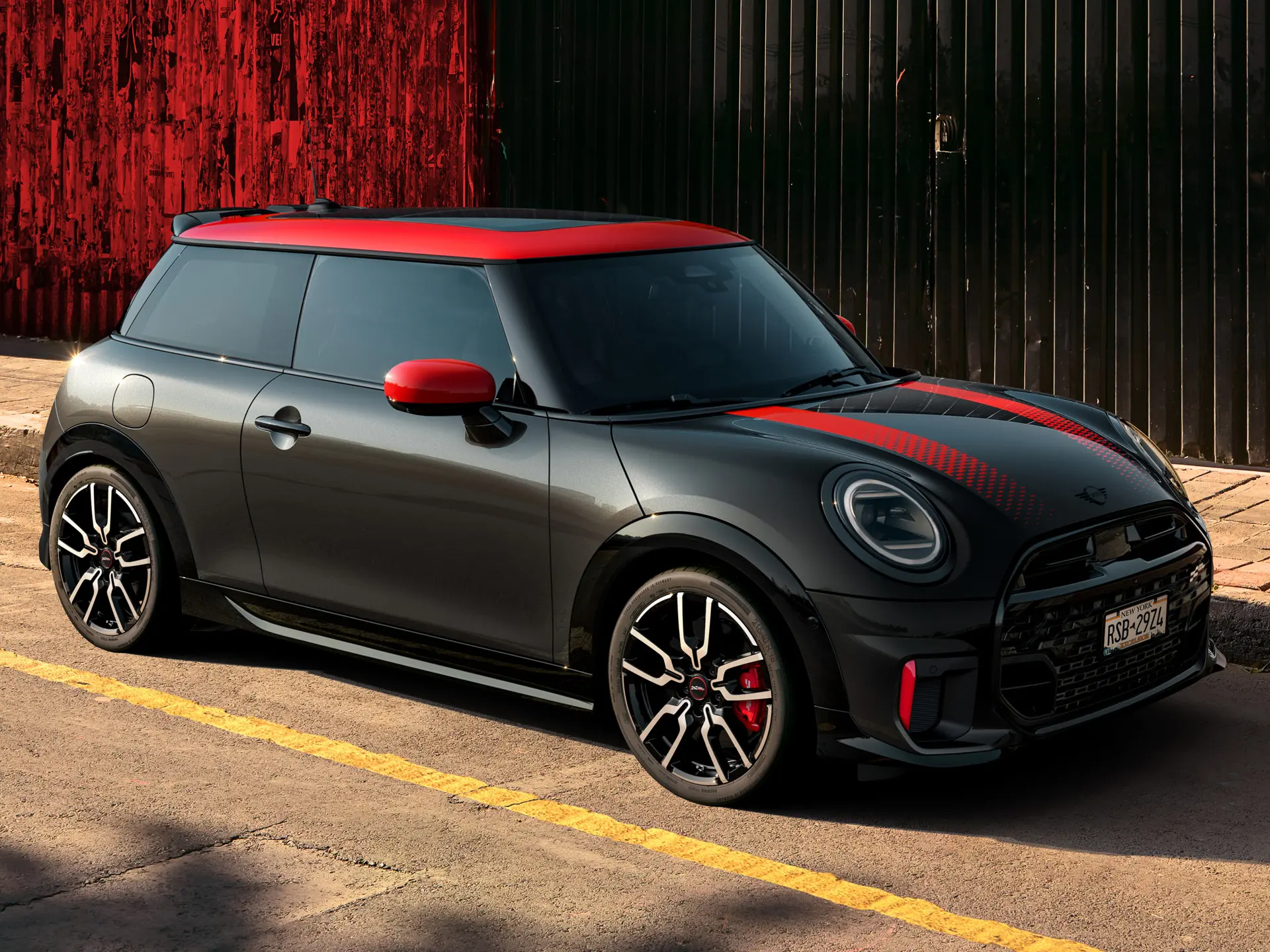 MINI John Cooper Works 3-Türer in Midnight Black mit Dach und Spiegelkappen in Chili Red und Sportstreifen rot, Seitenansicht, geparkt auf der Straße.
