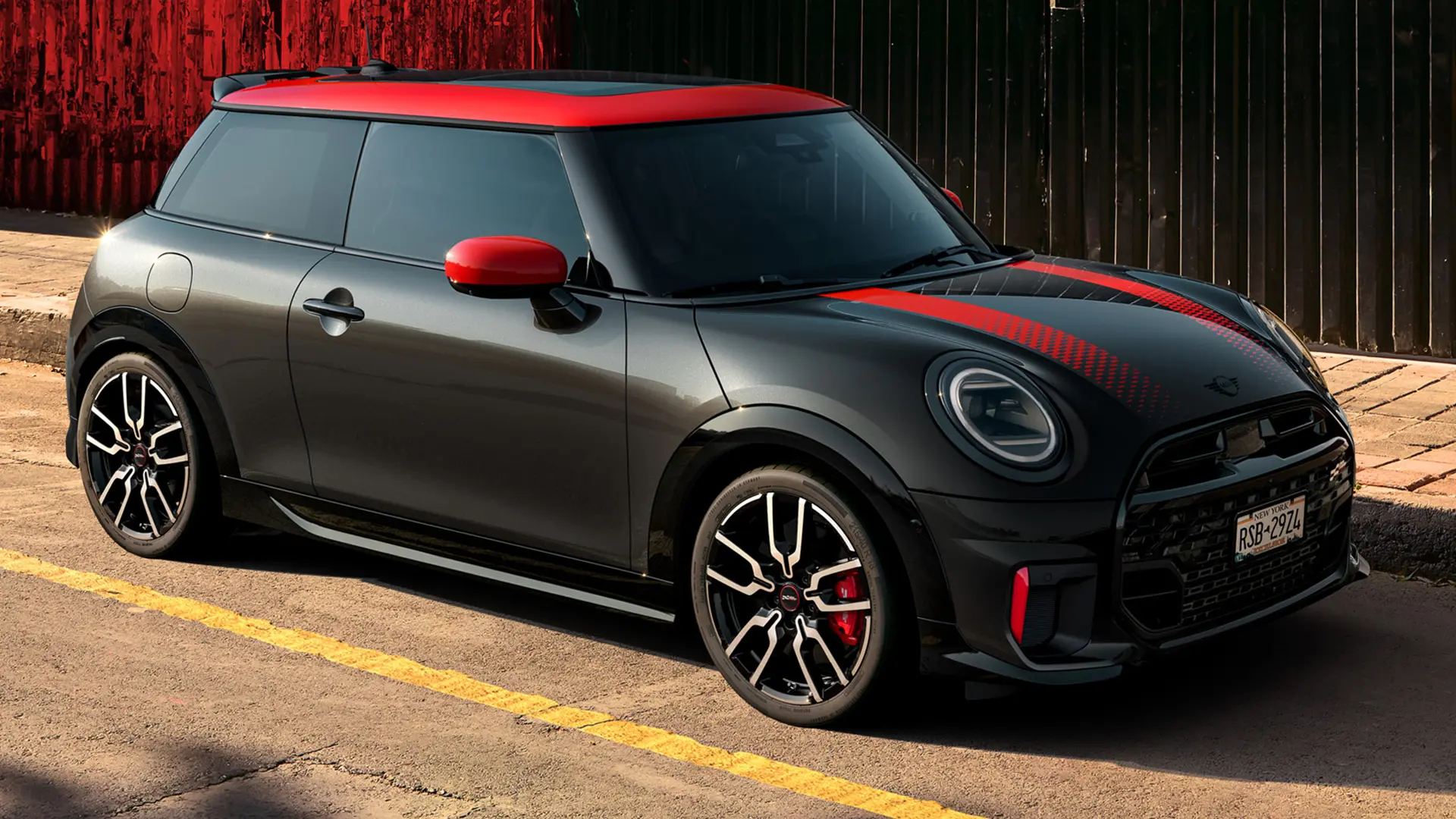MINI John Cooper Works 3-Türer in Midnight Black mit Dach und Spiegelkappen in Chili Red und Sportstreifen rot, Seitenansicht, geparkt auf der Straße.