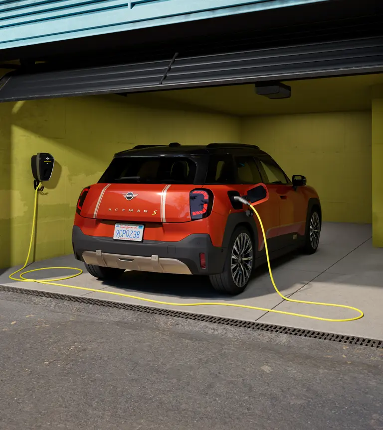 Der vollelektrische MINI Aceman S wird mit der MINI Wallbox Plus geladen, Rückansicht, geparkt in der Garage.