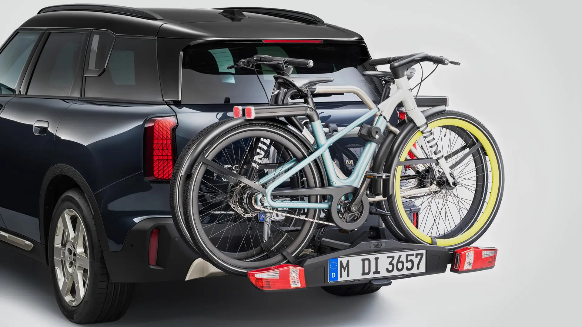 MINI Countryman in schwarz mit Fahrradheckträger und zwei Mountainbikes, Rückansicht.