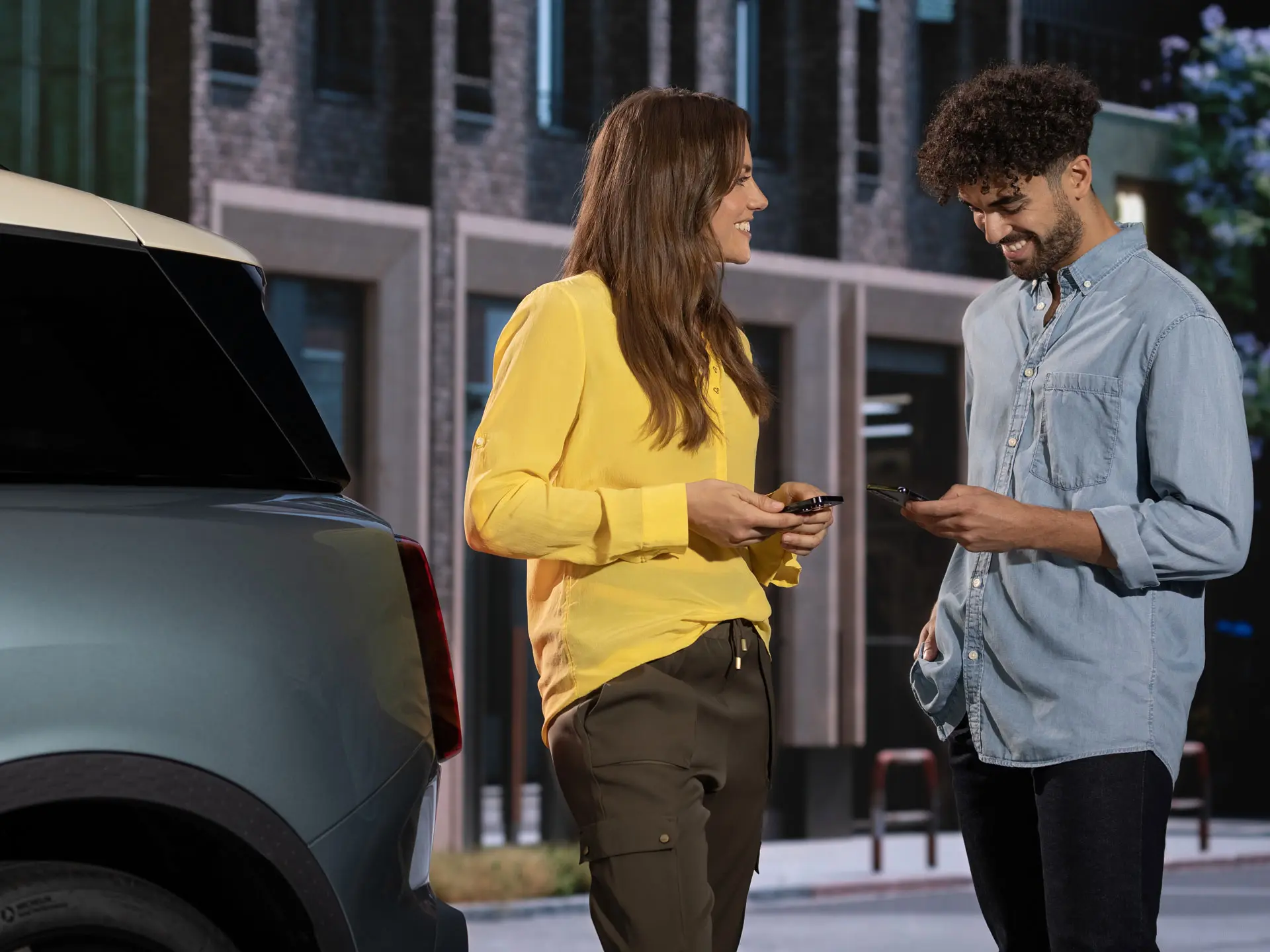 Mann und Frau stehen neben einem MINI und kontaktieren mit ihren Telefonen einen MINI Service Partner