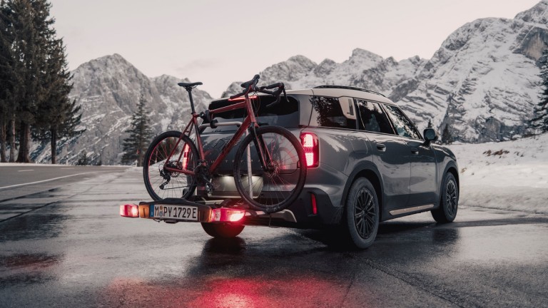 MINI Countryman in Smokey Green mit MINI Fahrradheckträger Pro 3.0, abgebildet mit zwei Mountainbikes in der Heckansicht.