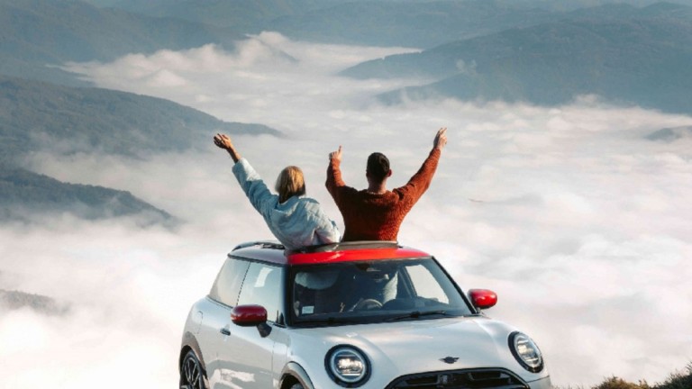 Paar jubelt in MINI mit Blick auf die Berge
