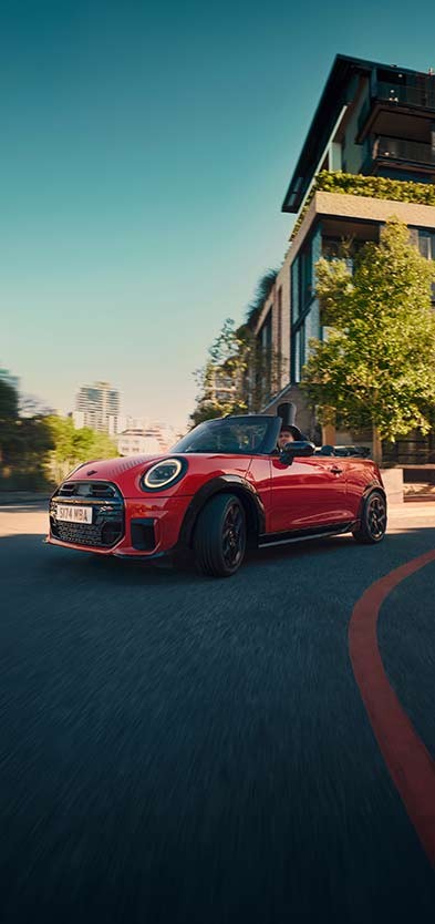 Heckansicht links eines parkenden MINI Cooper Cabrio am Strand mit zwei Personen