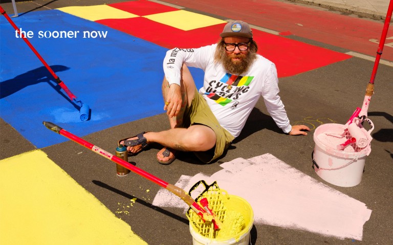 Florian Jöckel sitzt auf einem bunt bemalten Sportfeld. Am Mainufer hat er einen Urban Sports Park gestaltet.