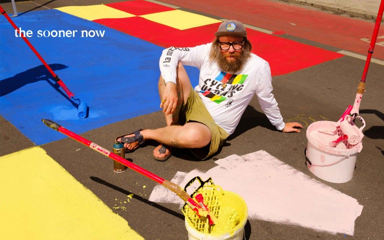 Florian Jöckel sitzt auf einem bunt bemalten Sportfeld. Am Mainufer hat er einen Urban Sports Park gestaltet.