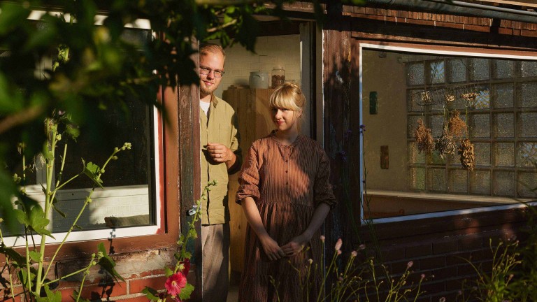 Anne Peter und Jens Amende stehen im Türrahmen ihrer Gartenlaube, die zu ihrem Schrebergarten „Nyponhus“ gehört. 