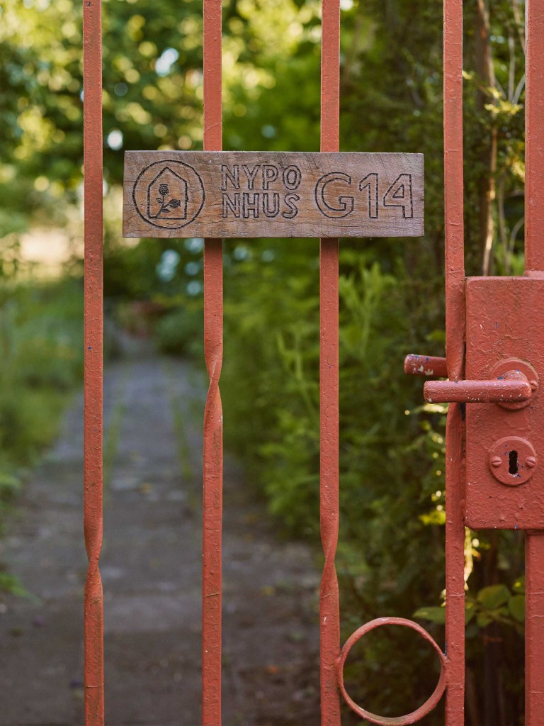 Nahaufnahme des rostroten Gartentors, das zum Schrebergarten „Nyponhus“ führt.