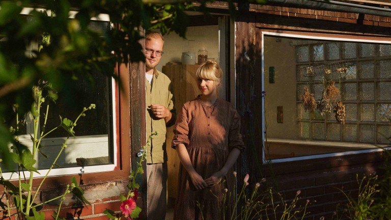Anne Peter und Jens Amende stehen im Türrahmen ihrer Gartenlaube, die zu ihrem Schrebergarten „Nyponhus“ gehört.